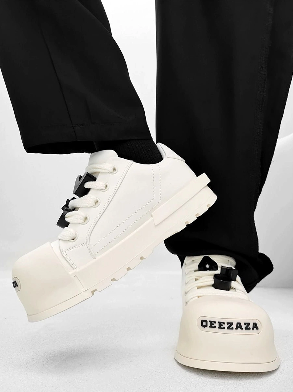 White oversized toe platform sneakers in a dynamic side view with elevated chunky rubber sole and lace-up design