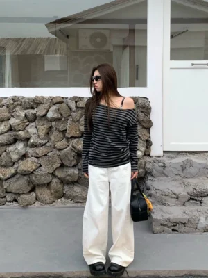 White panel-seam wide-leg jeans shown in a full-body front view with a relaxed streetwear silhouette and floor-grazing leg