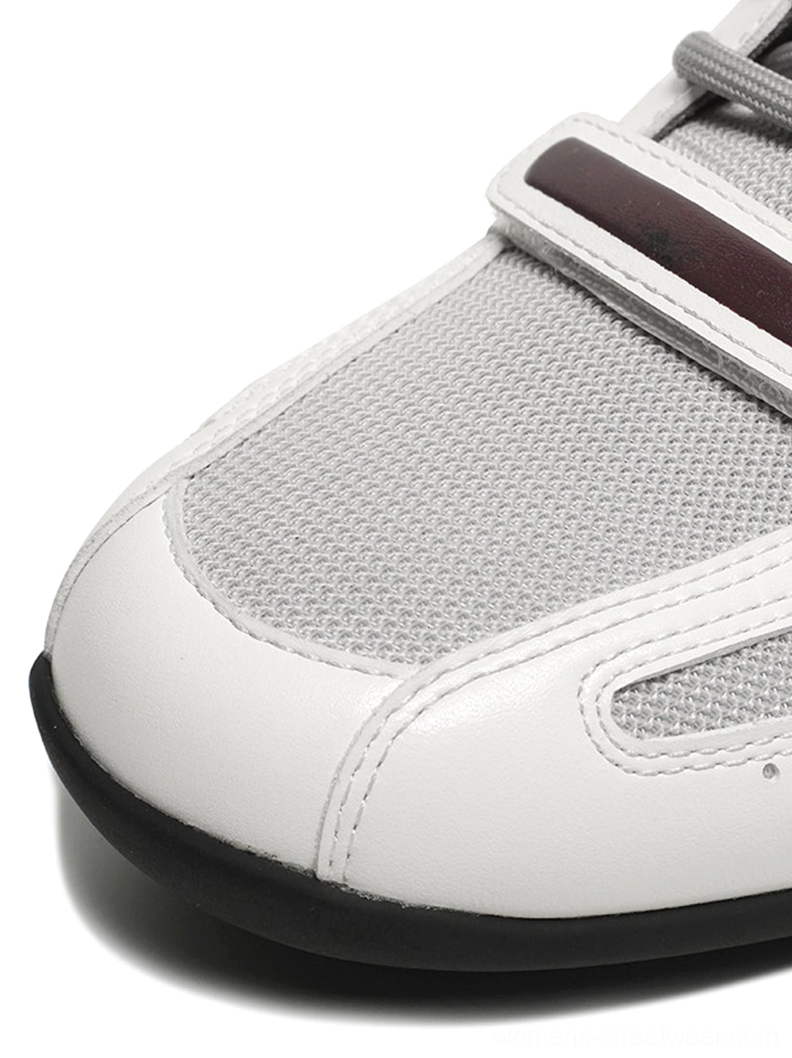 Close-up of white perforated retro sport sneaker toe with smooth toe cap grey panel burgundy strap and neat stitching