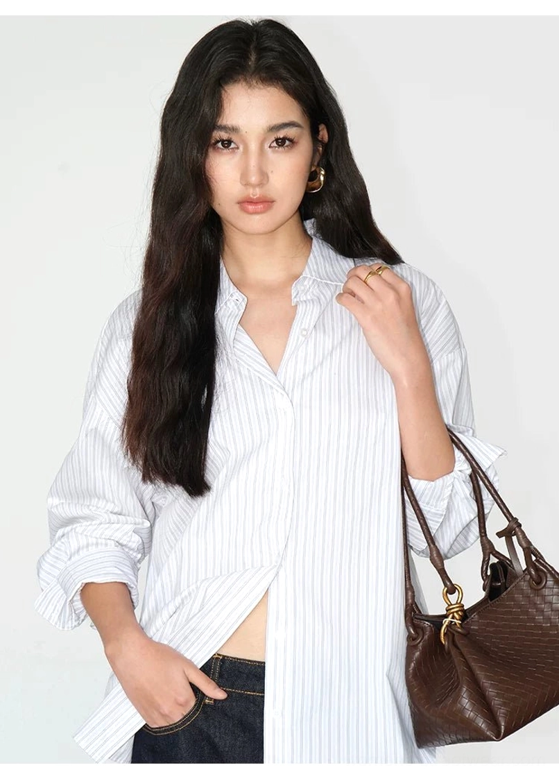 White pinstripe relaxed oversized button-up shirt half tucked into dark wash jeans