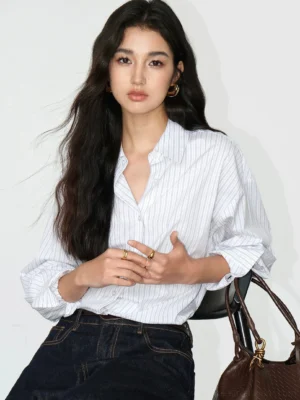 White pinstripe relaxed oversized cotton blend button-up shirt styled with dark denim jeans and leather tote