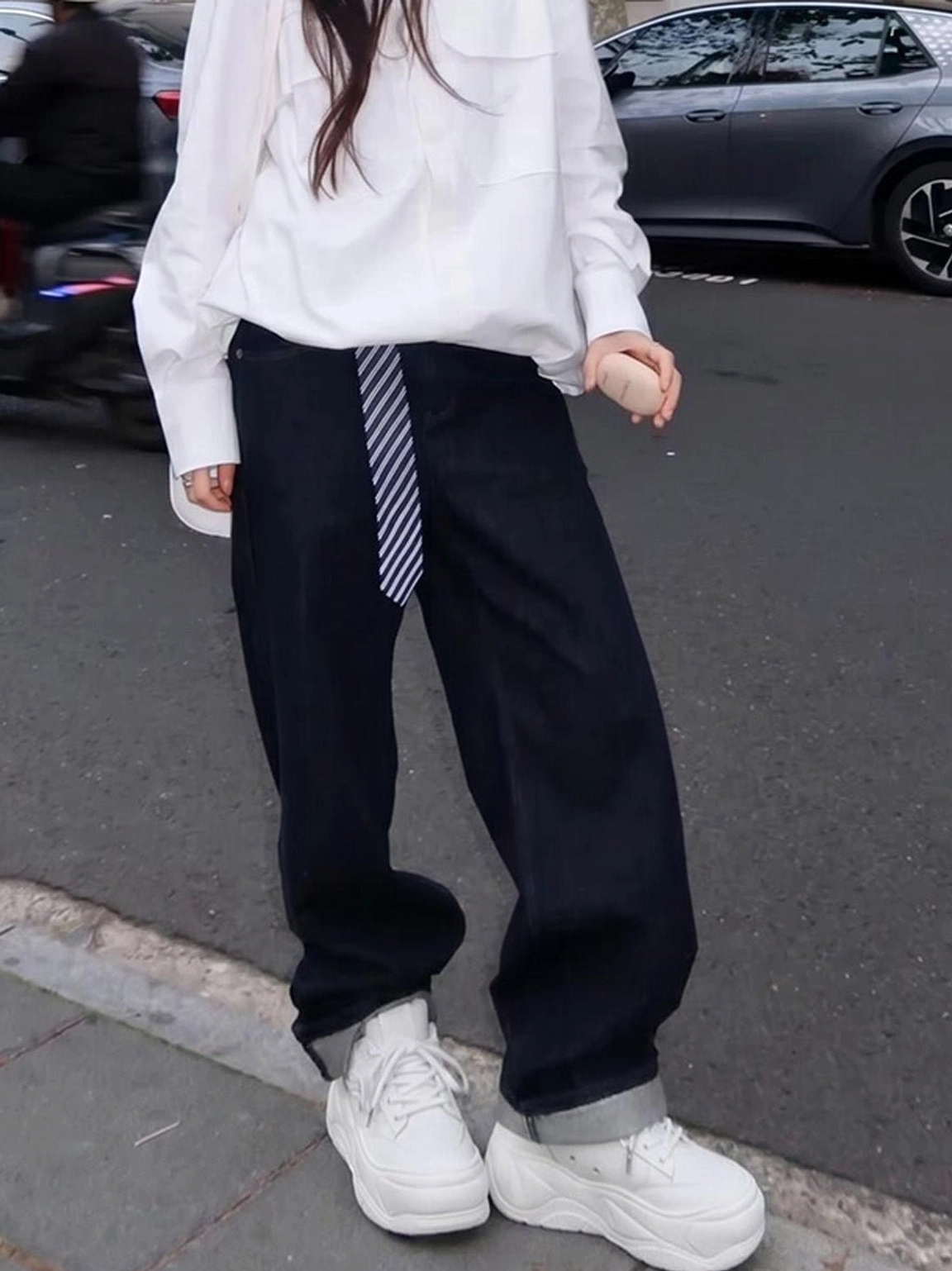 White platform sneakers styled with a white shirt and wide-leg dark jeans for a modern casual streetwear look