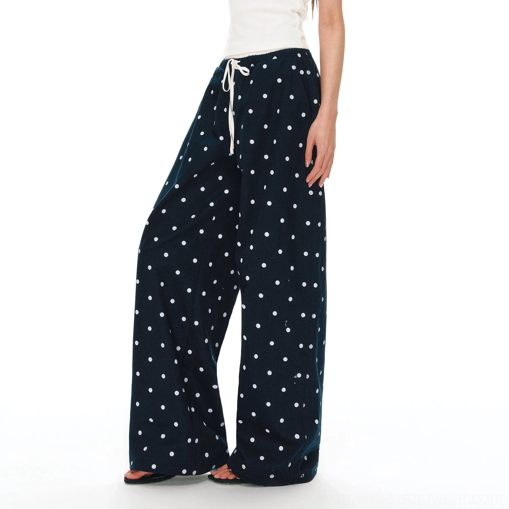 White polka dot drawstring wide leg pants shown from a low side view with red waist cord and relaxed streetwear styling
