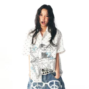 Front view of a white polka dot graphic camp shirt with cartoon artwork styled with printed wide-leg jeans