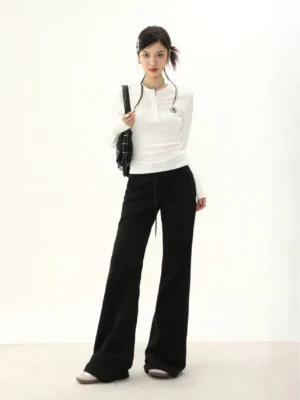 White ribbed half-button Henley long-sleeve streetwear top with thumb-hole sleeves styled with black wide-leg pants and a crossbody bag