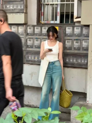 White ribbed slim-fit crew neck tank top for women paired with high-waisted flared jeans on a street
