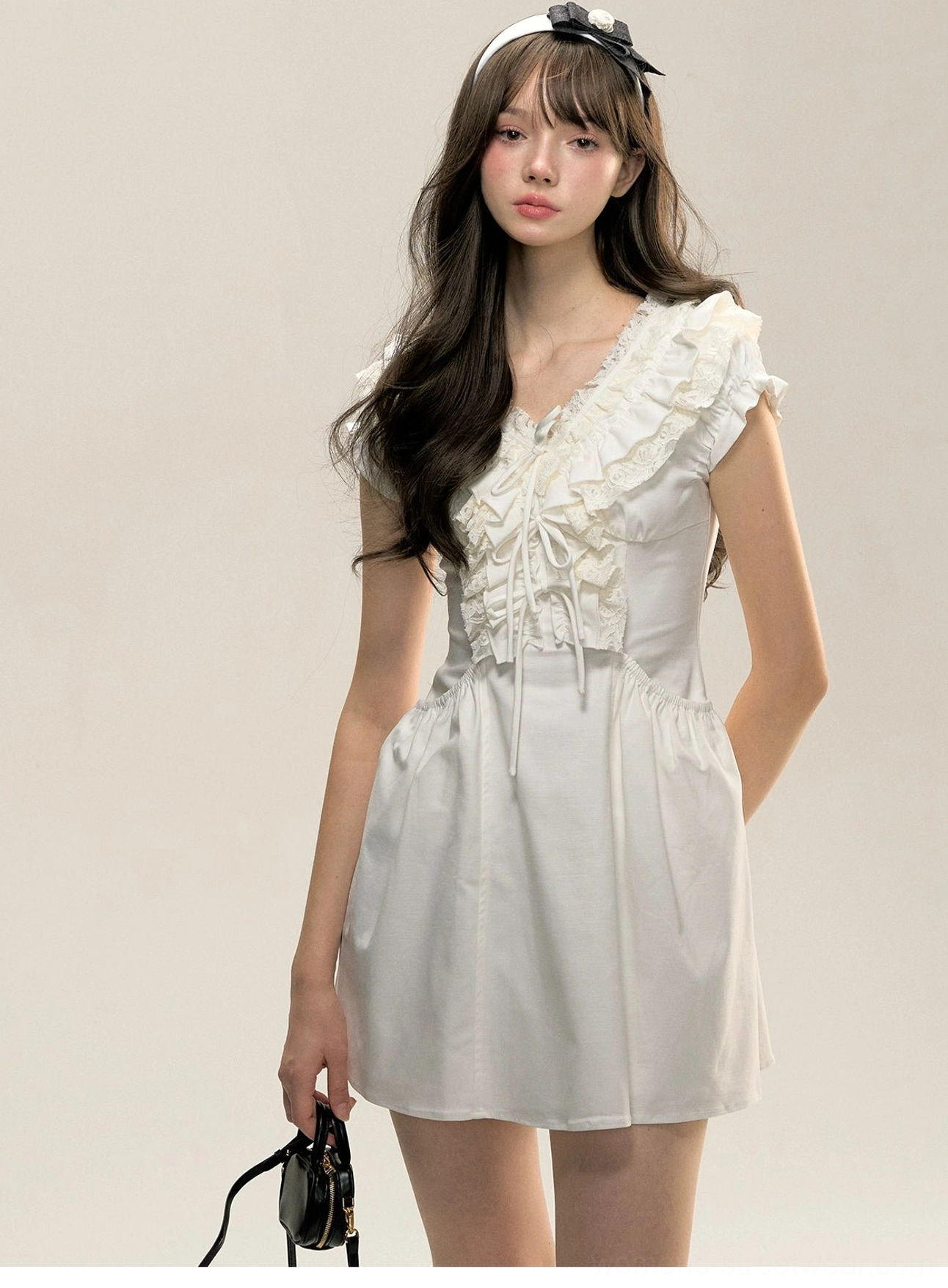 White ruffle cotton Victorian mini dress three-quarter front view styled with a black mini handbag