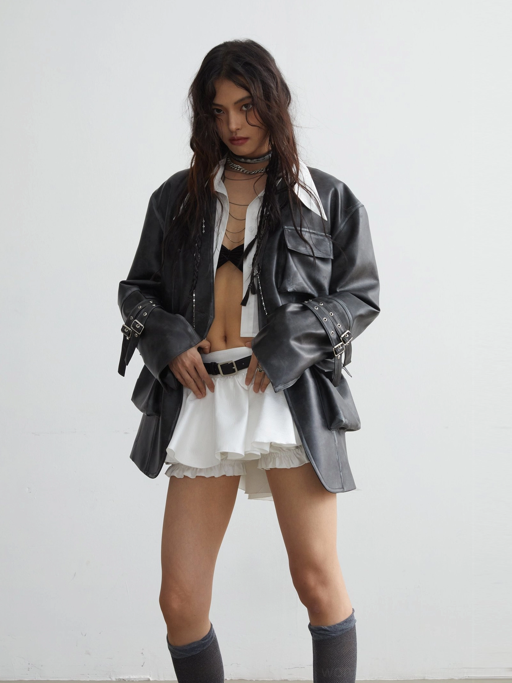Front three quarter view of white ruffled mini skirt with black belt detail and vintage washed jacket