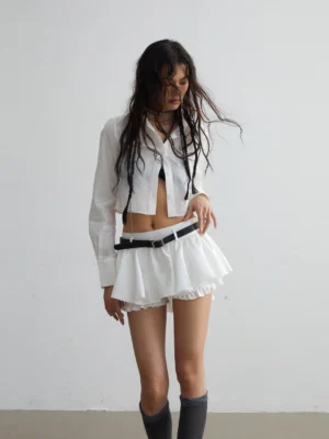 Front full body view of white ruffled belted mini skirt styled with cropped white shirt and dark knee high socks