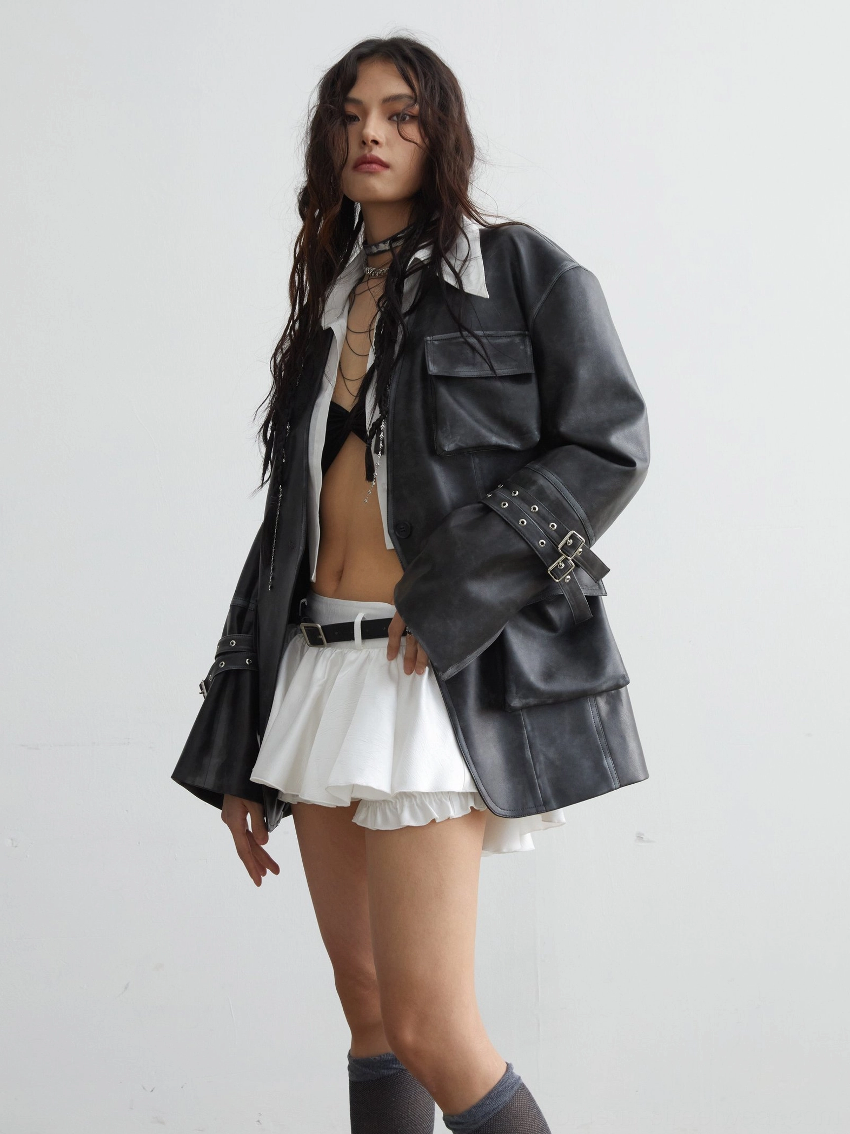 White ruffled mini skirt with belt embellishment styled with cropped shirt bralette layered necklaces and knee socks