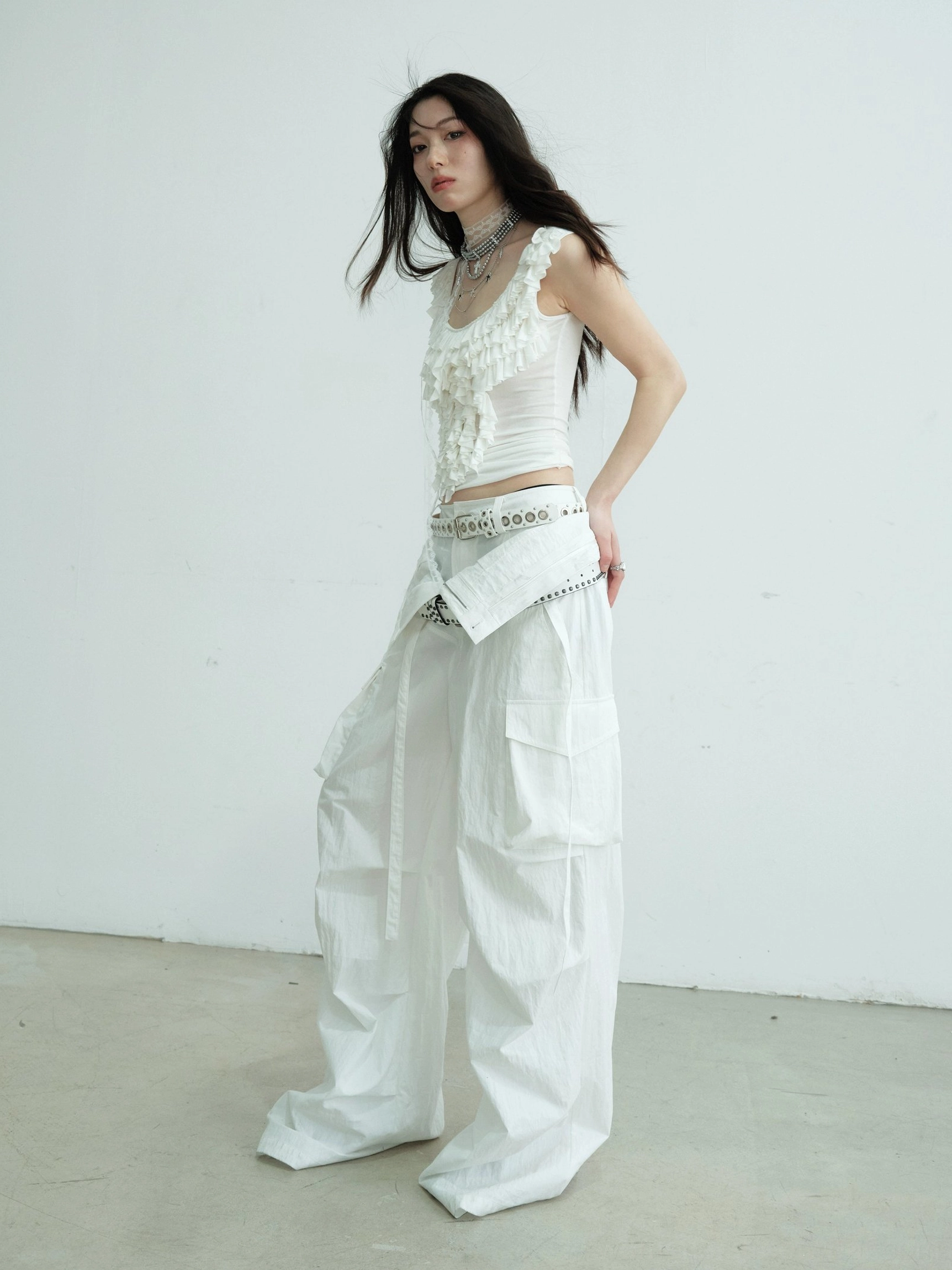 Side view of white ruffled lace scoop neck slim tank top paired with white cargo pants in Korean streetwear styling