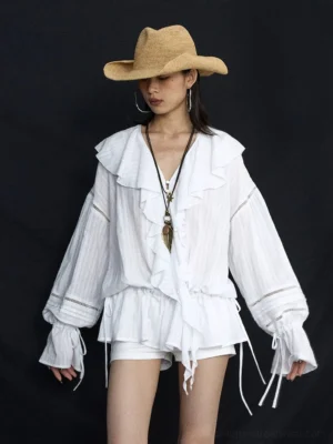 White ruffled poet blouse with drawstring hem and ladder-lace sleeves styled with white shorts and a straw cowboy hat