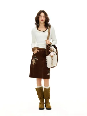 White ruffled scoop neck slim knit top styled with a brown embroidered skirt and suede boots