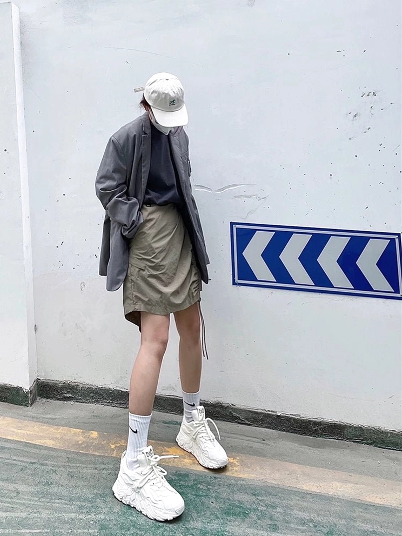 White sculpted chunky streetwear sneakers styled with a cap blazer and mini skirt in a contemporary urban fashion outfit