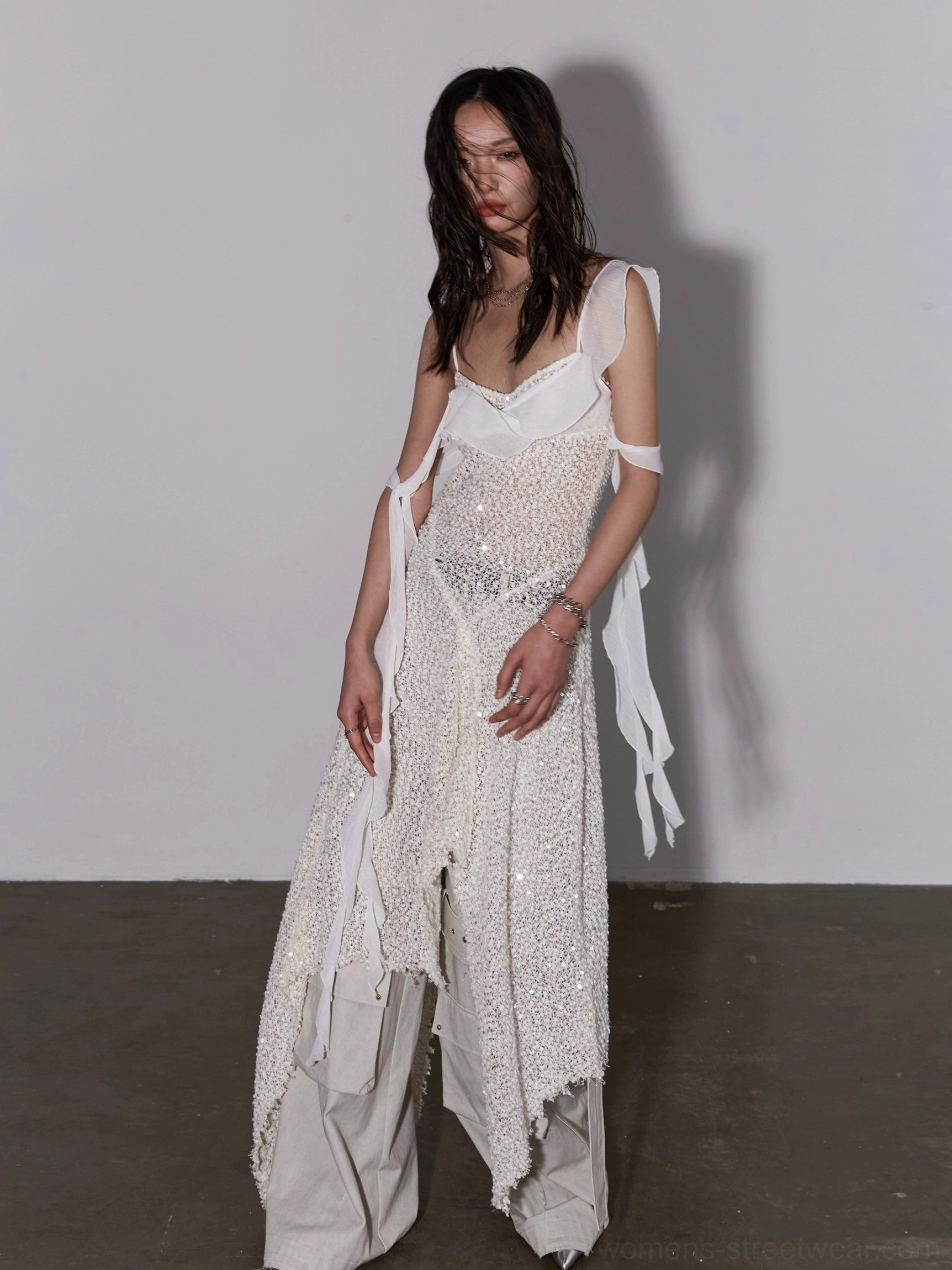 Side three quarter streetwear styling of white sequined asymmetric layered dress over relaxed cargo pants