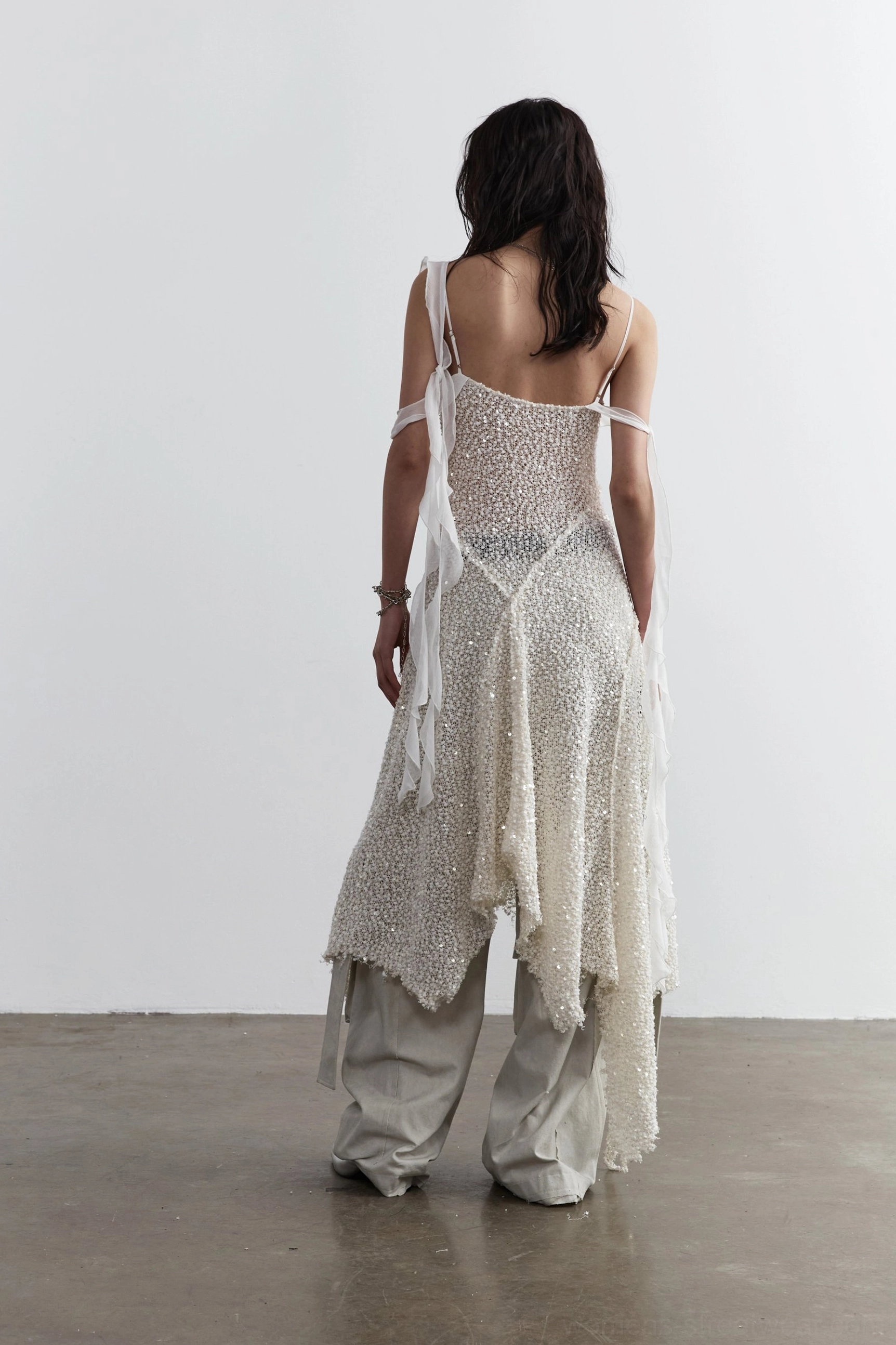 Back view of white sequined mesh layered slip dress showing open back cross wrap straps and frayed asymmetric hem