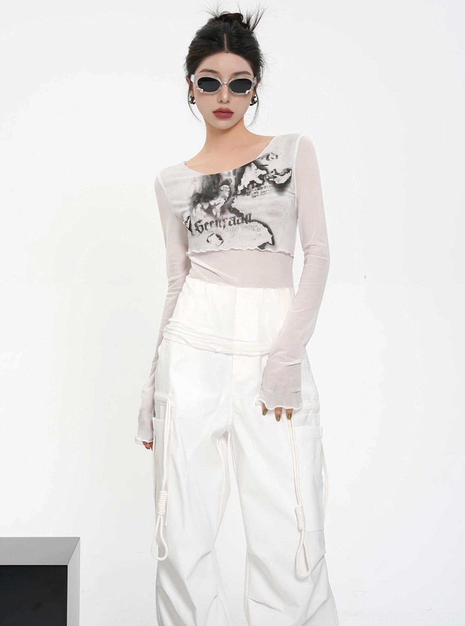White sheer mesh floral graphic long sleeve crop top with asymmetrical neckline styled with white cargo pants