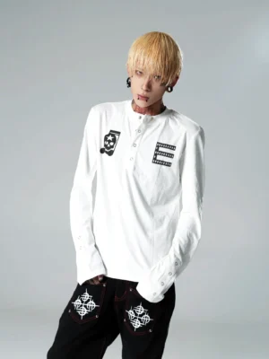 White skull graphic Henley long sleeve streetwear top shown on a model with half snap-button placket, chest glyph print, extended cuffs, and punk-inspired details