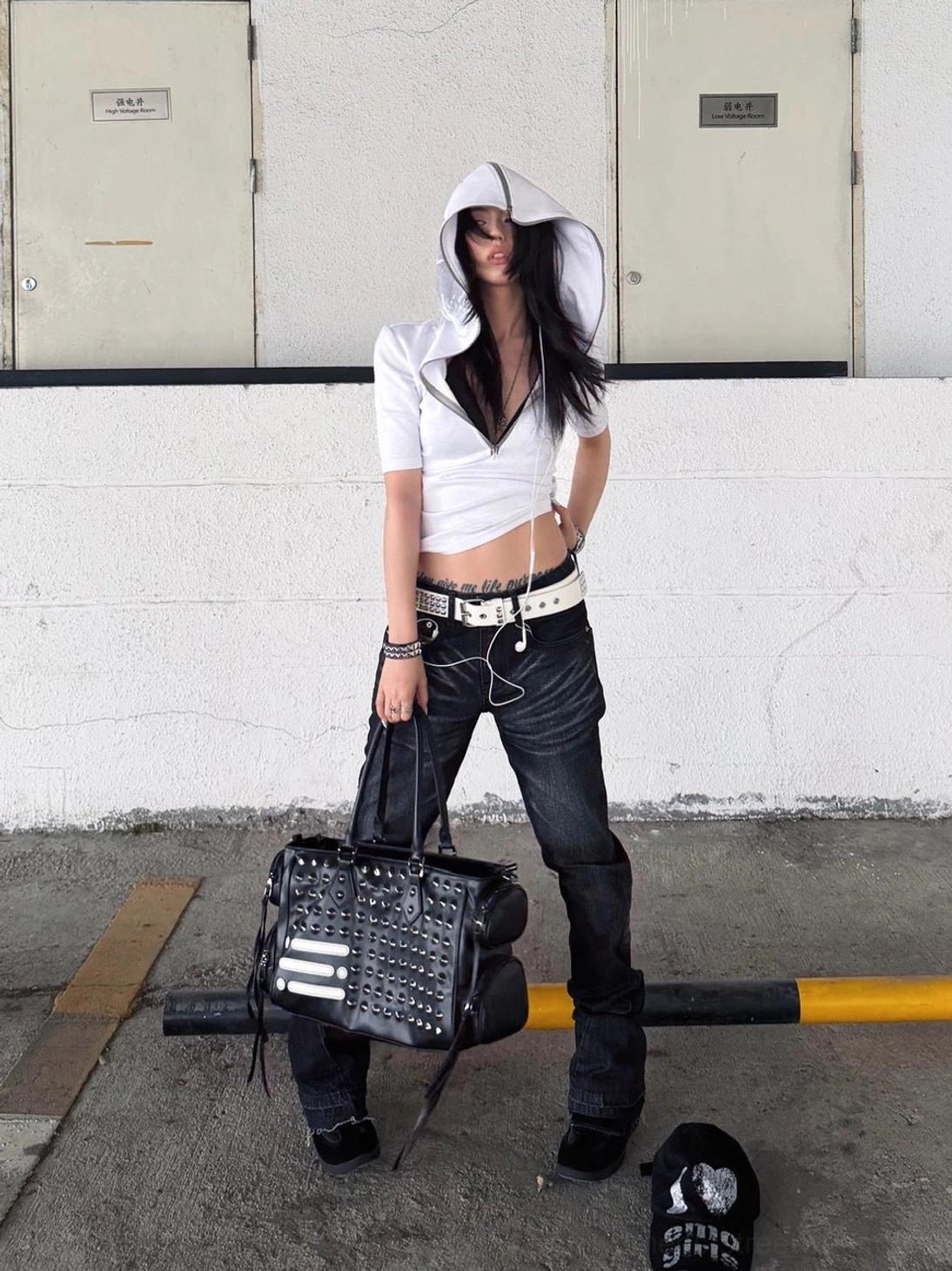 White cropped skull hooded streetwear tee with half-zip neckline styled with dark jeans and a studded black tote bag