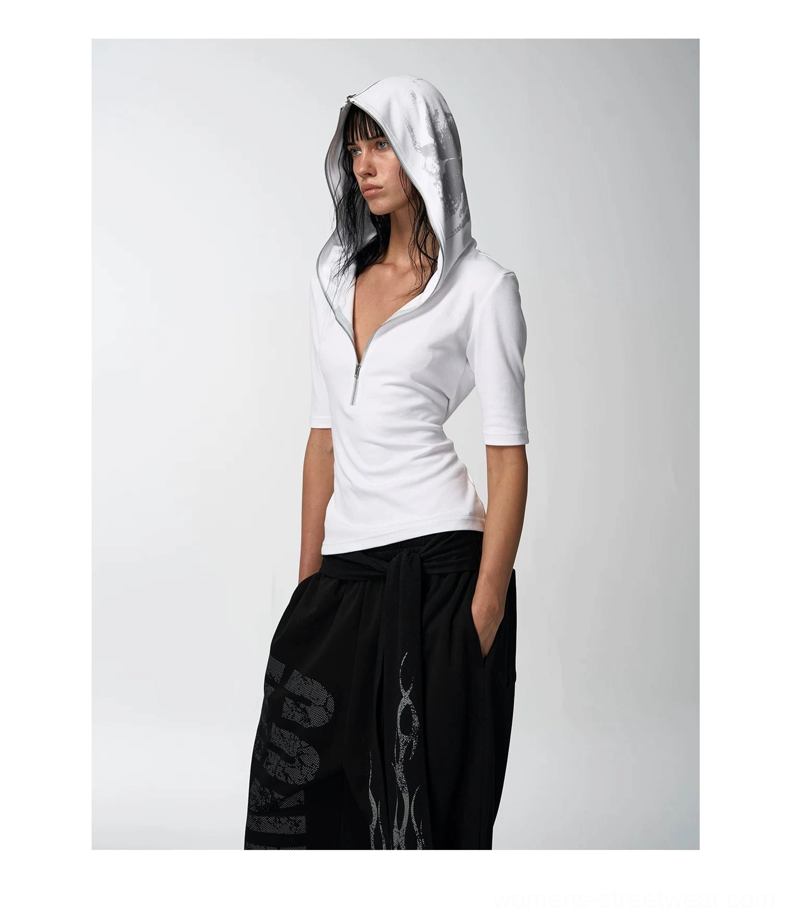 Full-body front view of a white fitted skull hooded tee styled with relaxed black wide-leg streetwear trousers