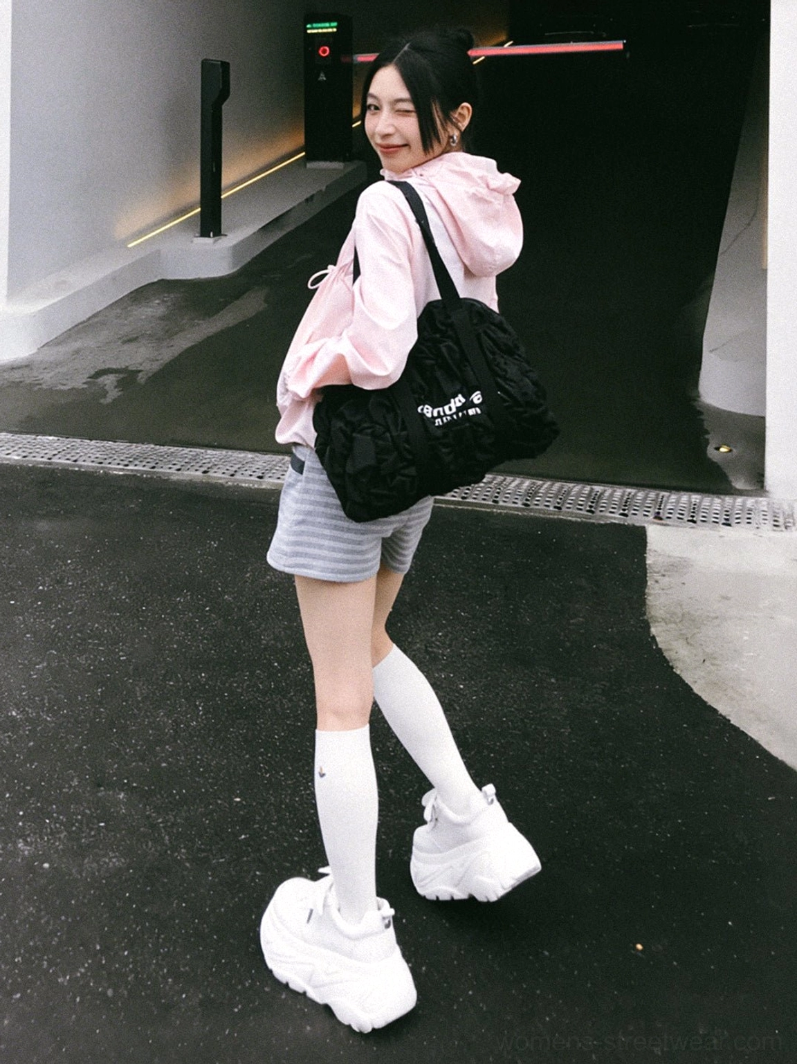 White square-toe platform sneakers styled with a pink hoodie, striped shorts, and knee-high socks in an urban setting