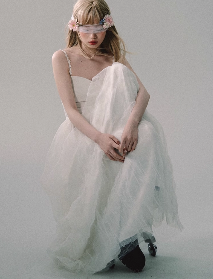 Full-body seated view of white sweetheart tulle gown with lace straps, fitted bodice, soft draped skirt, and floor-length silhouette