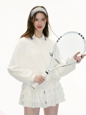 White tennis preppy two piece polo skirt set with black striped collar, dual racket embroidery and layered ruffle hem shown in a front close up