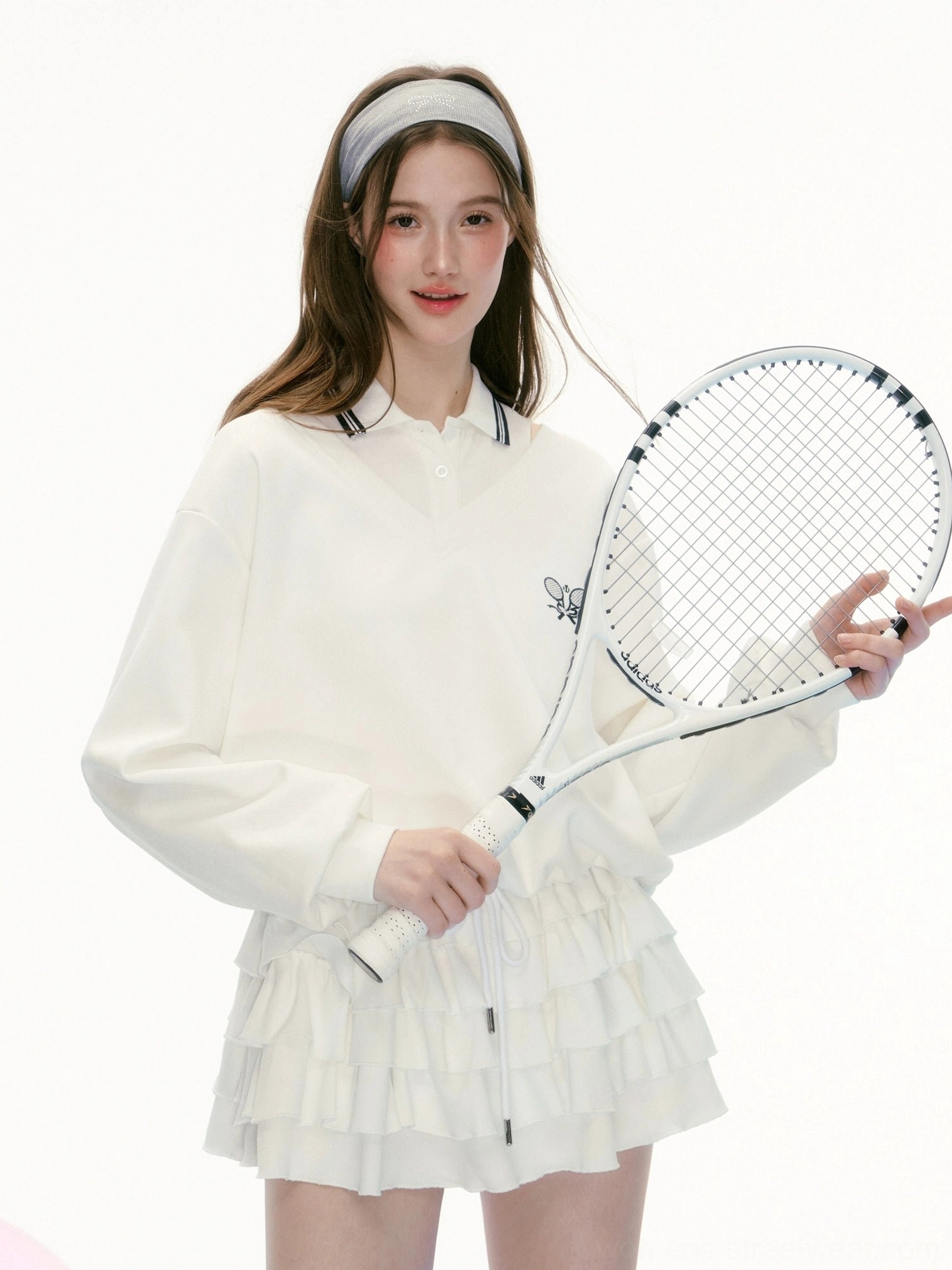White tennis preppy two piece polo skirt set with black striped collar, dual racket embroidery and layered ruffle hem shown in a front close up