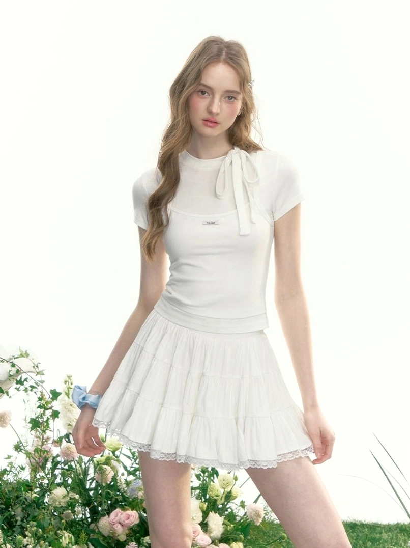 White tiered tennis skirt with lace trim styled with a white bow neck short sleeve top in a romantic Korean streetwear garden outfit