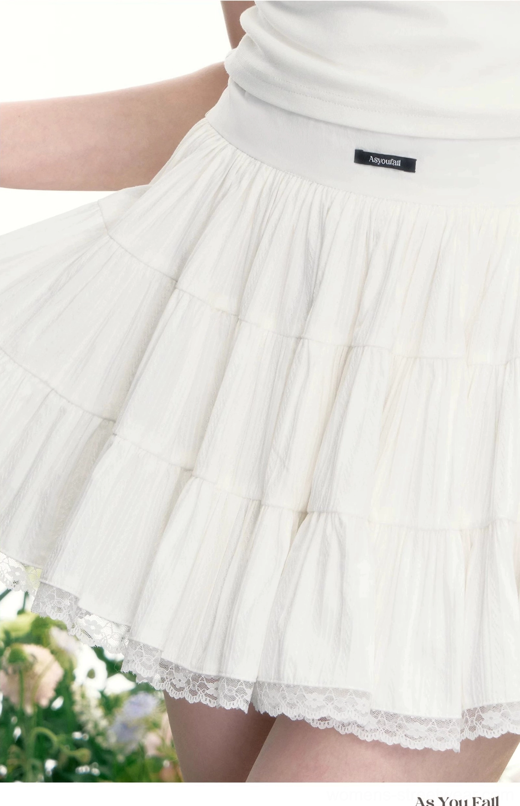 Close-up view of the white tiered tennis skirt showing layered ruffles, lace hem trim, and waistband detail