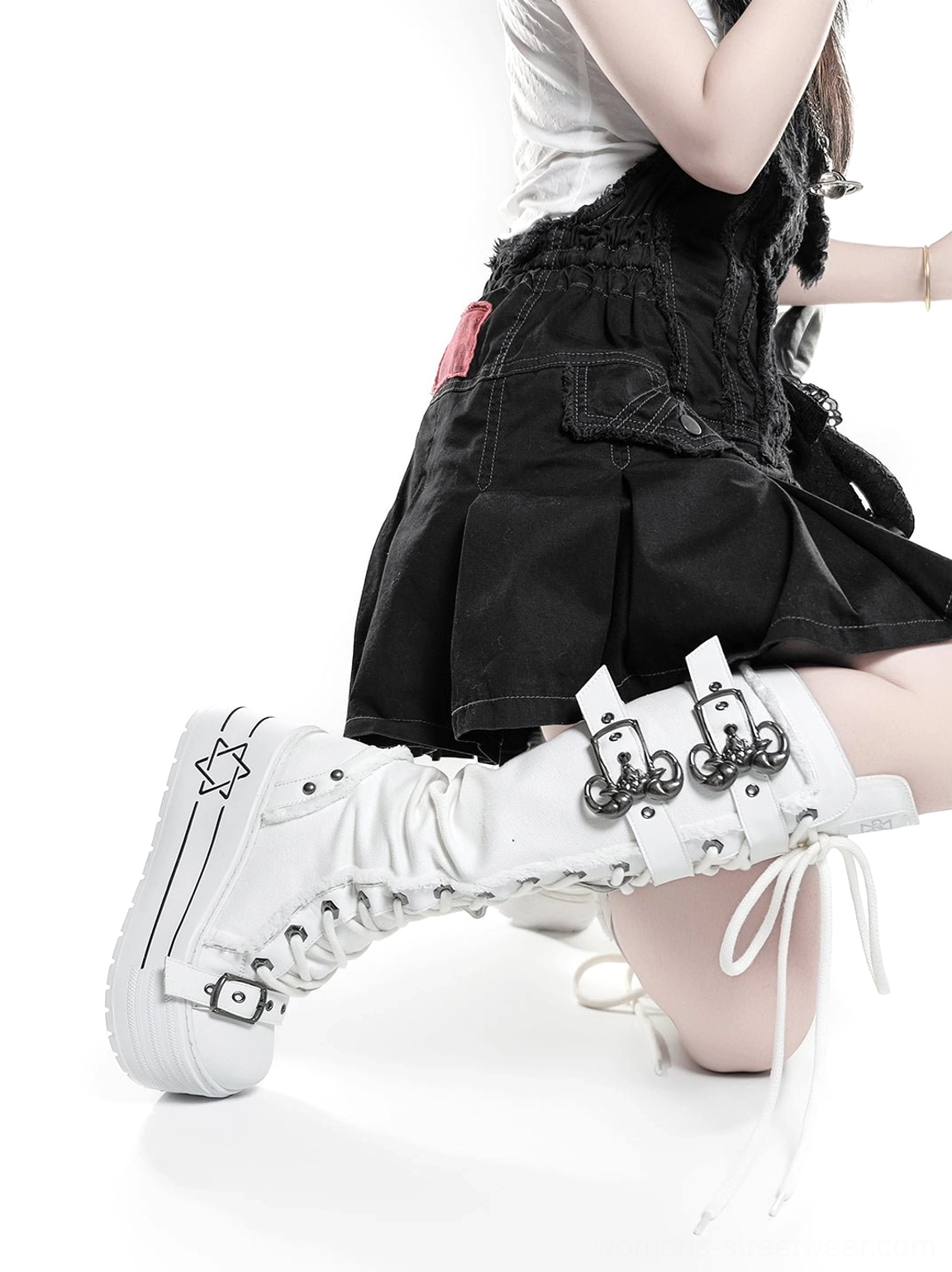 White knee-high platform combat boots with triple buckle straps and lace-up front worn with black alternative fashion outfit