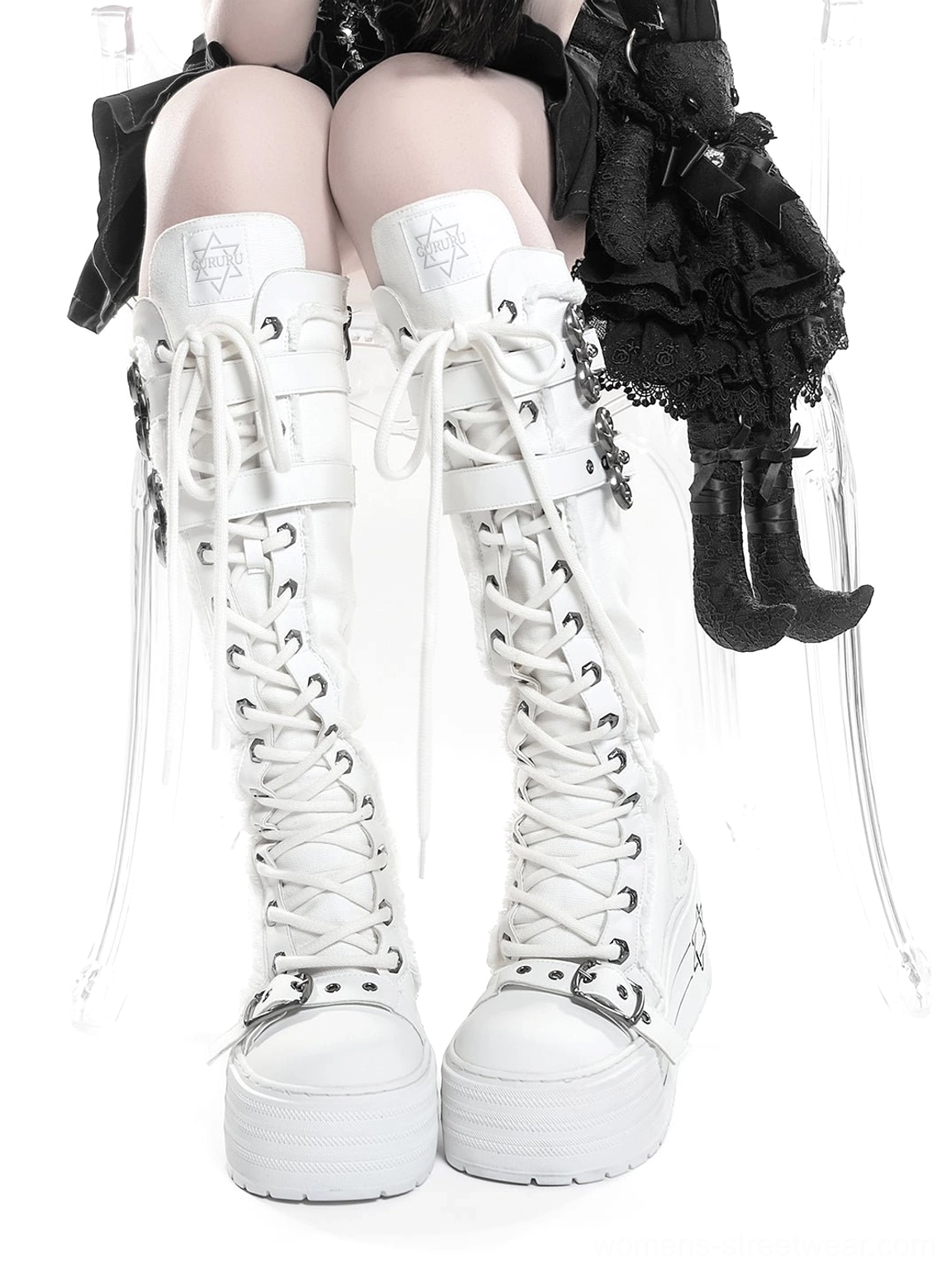 Front view of white triple-buckle knee-high platform combat boots worn with gothic streetwear outfit and long laces