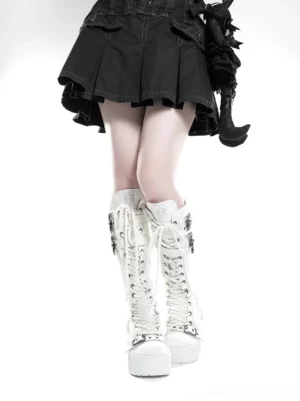 Model wearing white triple-buckle knee-high platform combat boots with a black gothic pleated mini skirt rear view