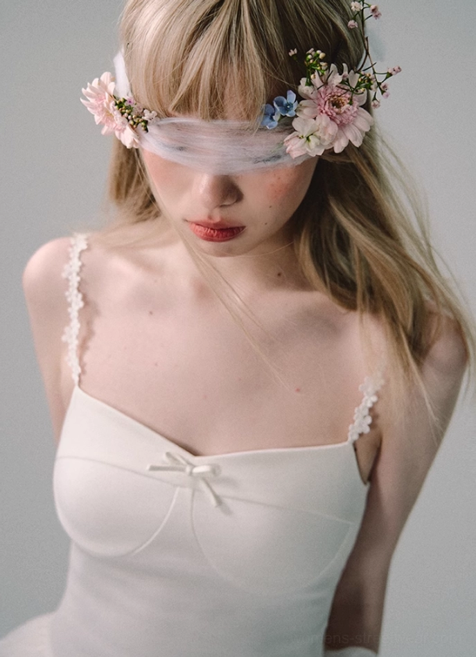 Side close-up of white tulle gown bodice showing lace-edged spaghetti strap, sweetheart neckline, satin bow, and fitted stretch silhouette
