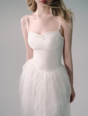 Close-up view of white tulle gown bodice with sweetheart neckline, petite satin bow, fitted shape, and lace-trimmed spaghetti straps