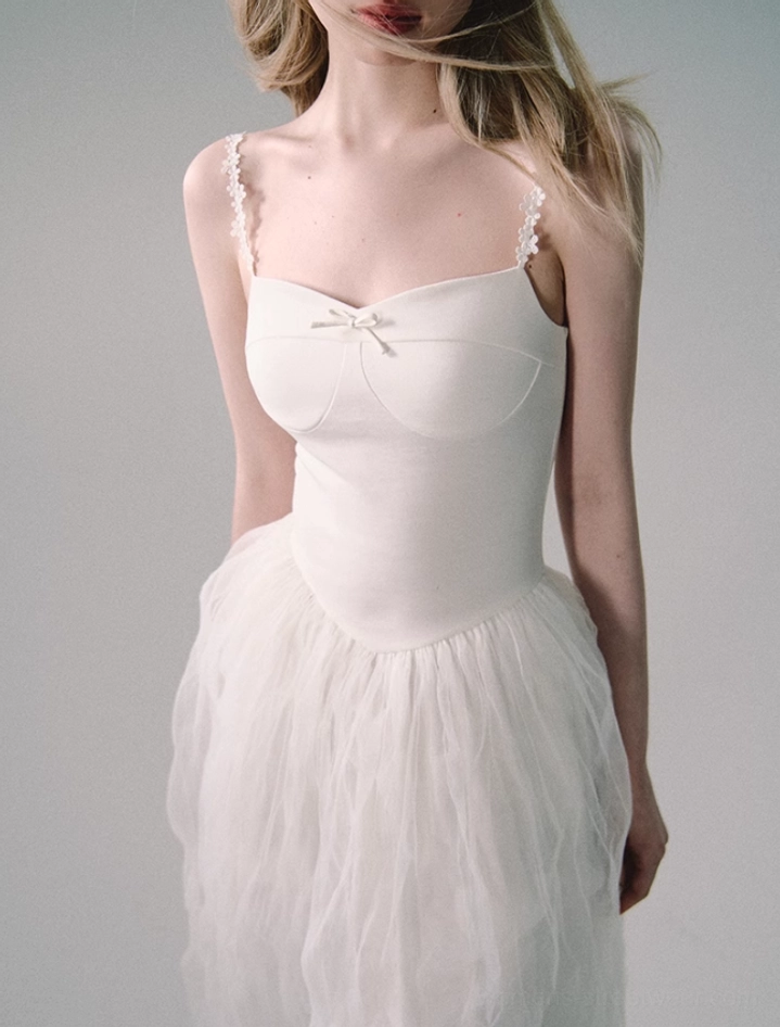 Close-up view of white tulle gown bodice with sweetheart neckline, petite satin bow, fitted shape, and lace-trimmed spaghetti straps