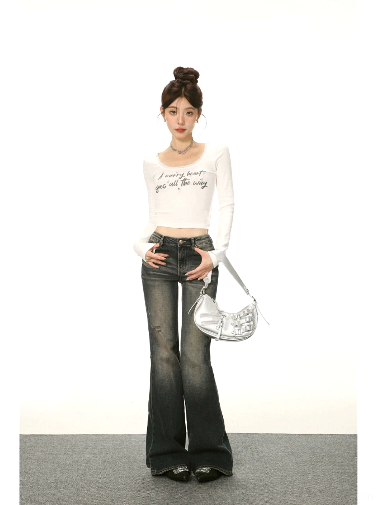 Full-body Korean streetwear outfit featuring a white U-neck lace trim cropped top, dark flared jeans, and a silver metallic shoulder bag