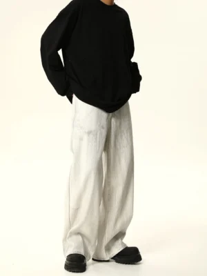 Angled front view of relaxed white washed wide leg jeans styled with an oversized black top and casual black boots