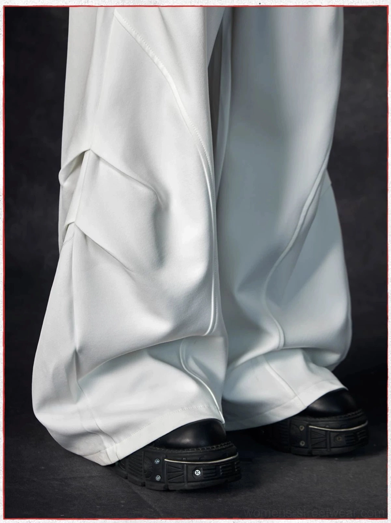 Close-up side detail of white wave contour wide-leg streetwear trousers showing thick 3D wave seams and smooth draped fabric