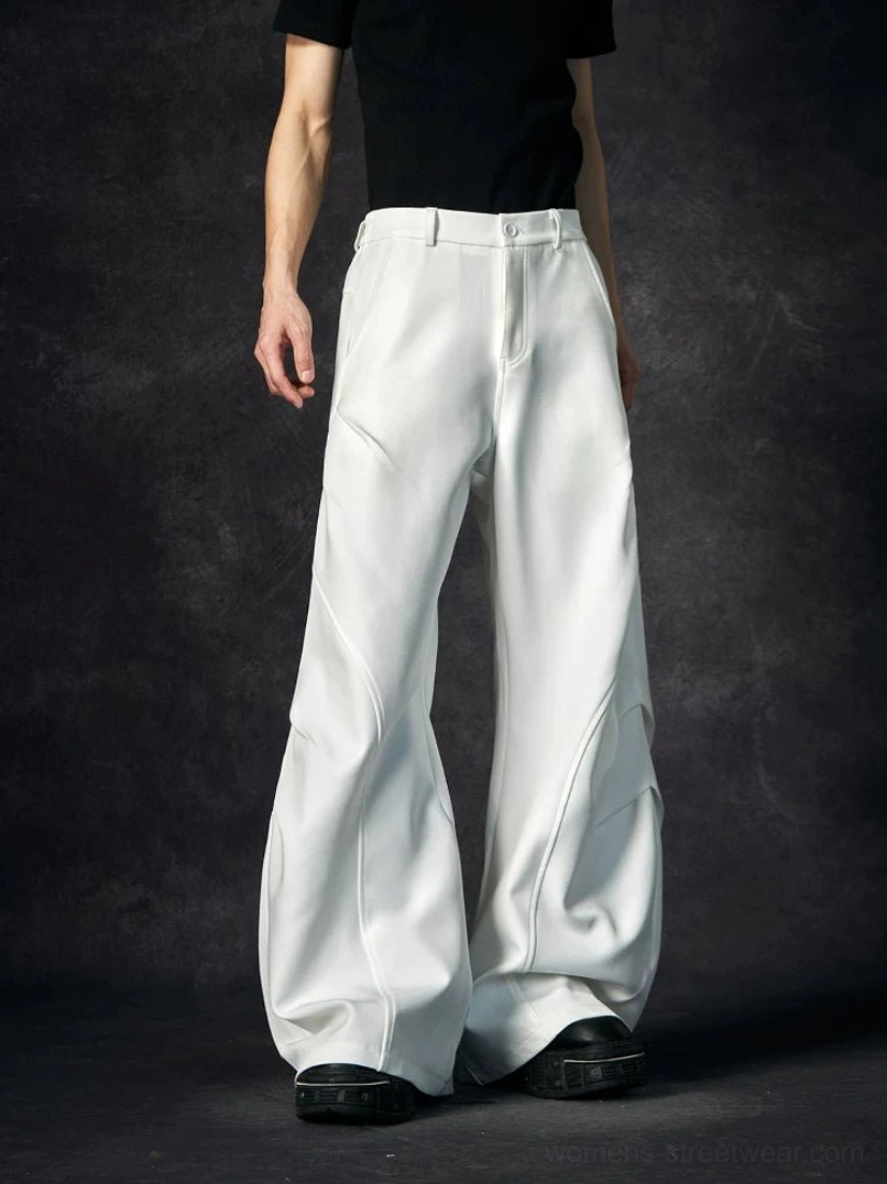 White wave contour wide-leg streetwear trousers shown from the front with sculptural curved seams, high-rise waistband, and exaggerated floor-length silhouette