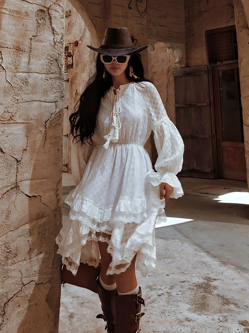 White western ruffle long sleeve midi dress with lace-up tie neckline tiered skirt and ruffled cuffs styled beside a vintage stone building