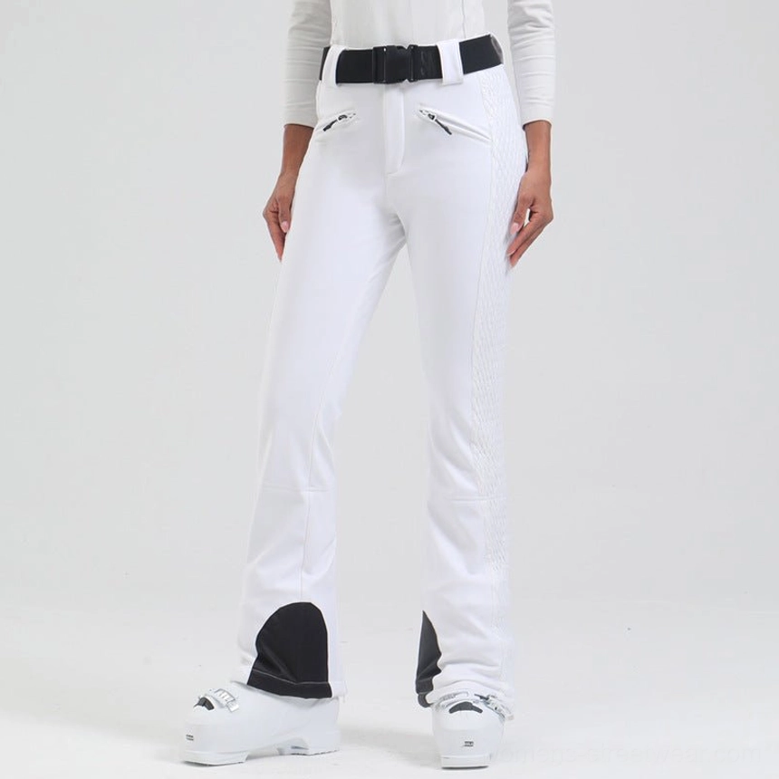 Low angle front side view of white women's flared snow pants with quilted side panels, black heel patches, and ski boots