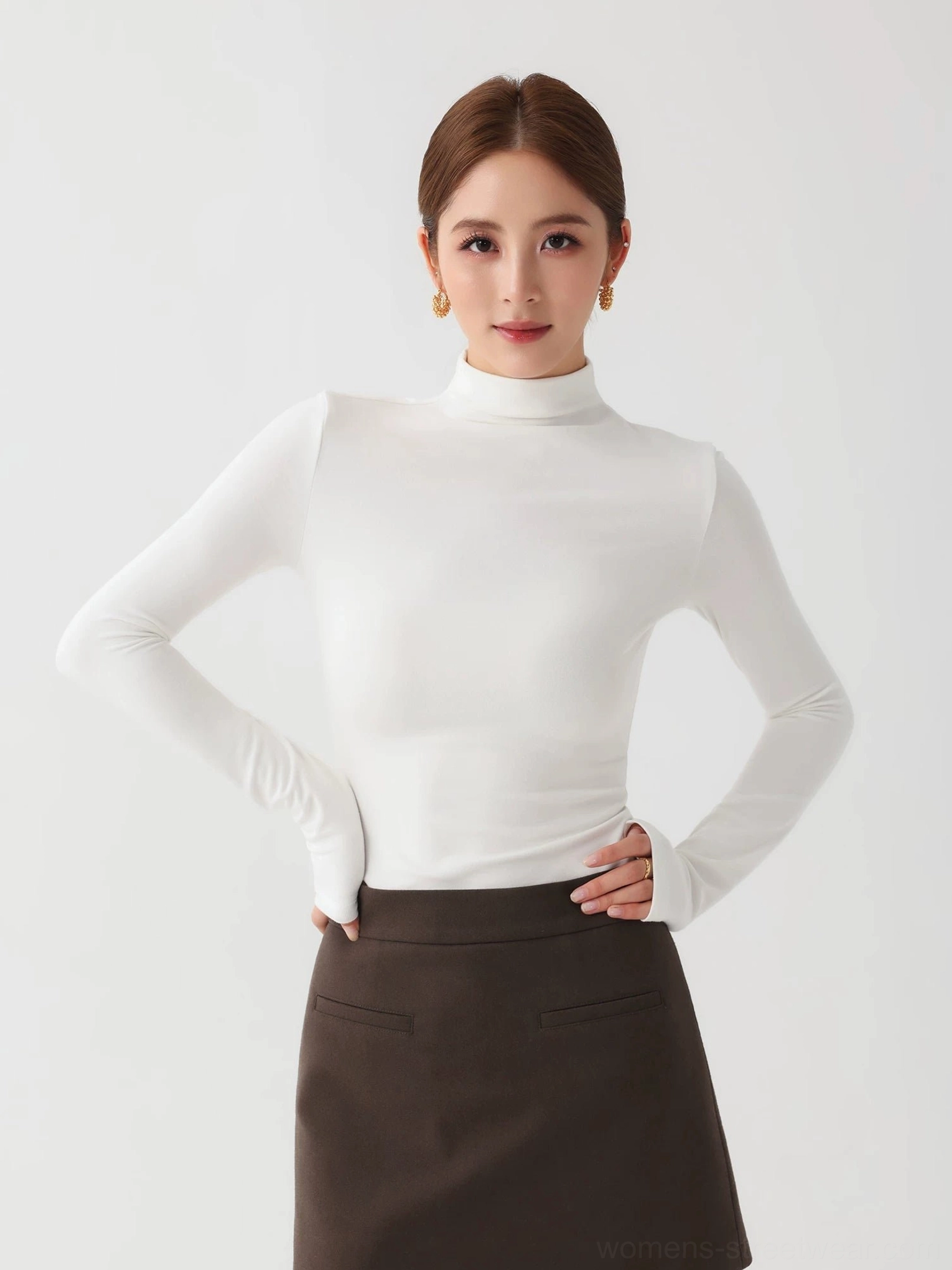 White women's slim fit mock neck knit top with long sleeves styled with a dark brown mini skirt