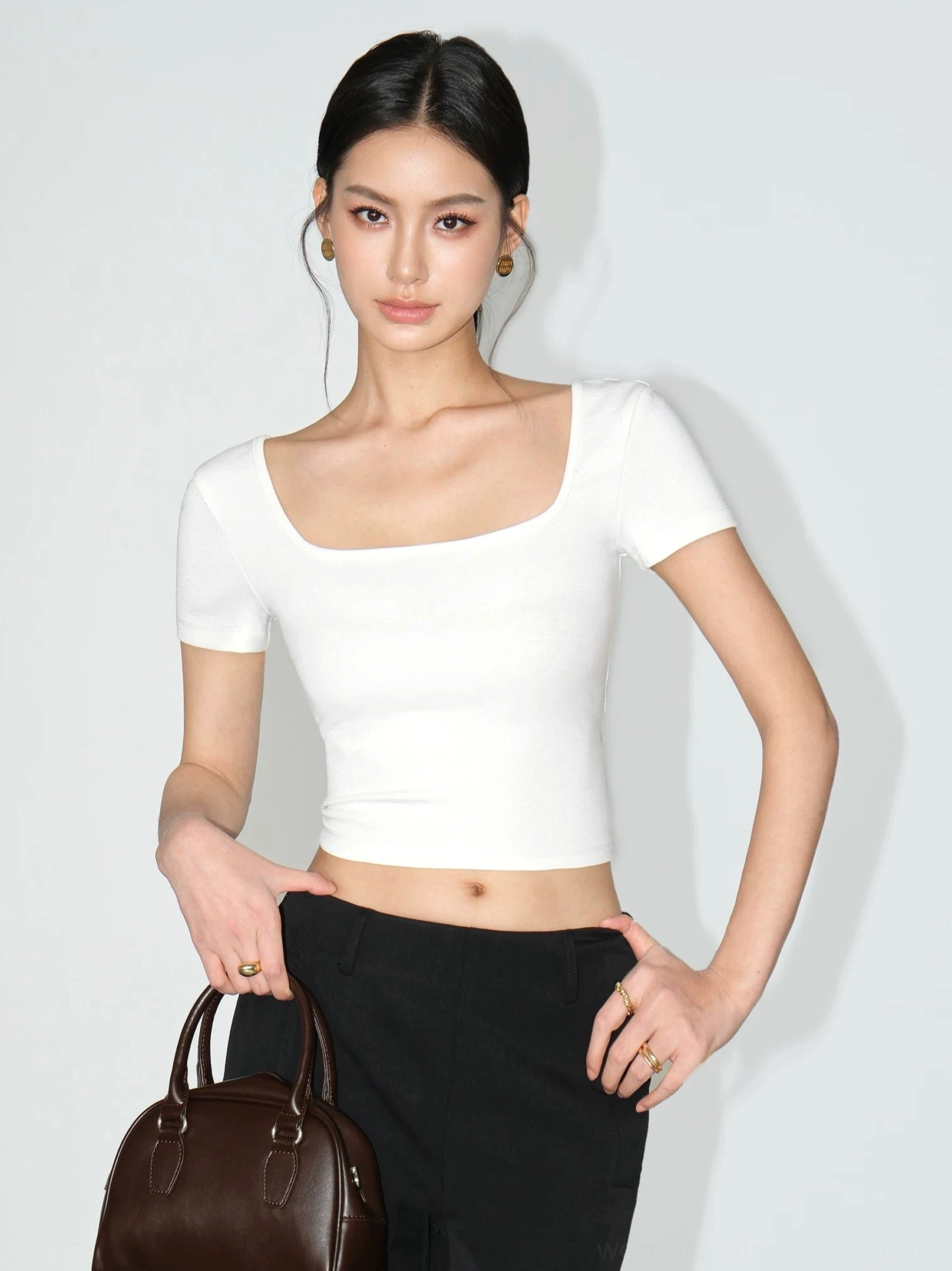 White women's square neck cropped fitted ribbed tee paired with high waisted black trousers and a leather handbag