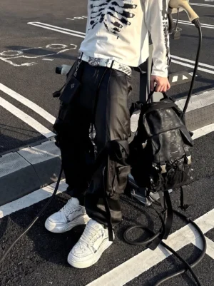 White sculpted platform sneakers styled with black cargo pants, skeleton print top, and backpack in an urban streetwear outfit