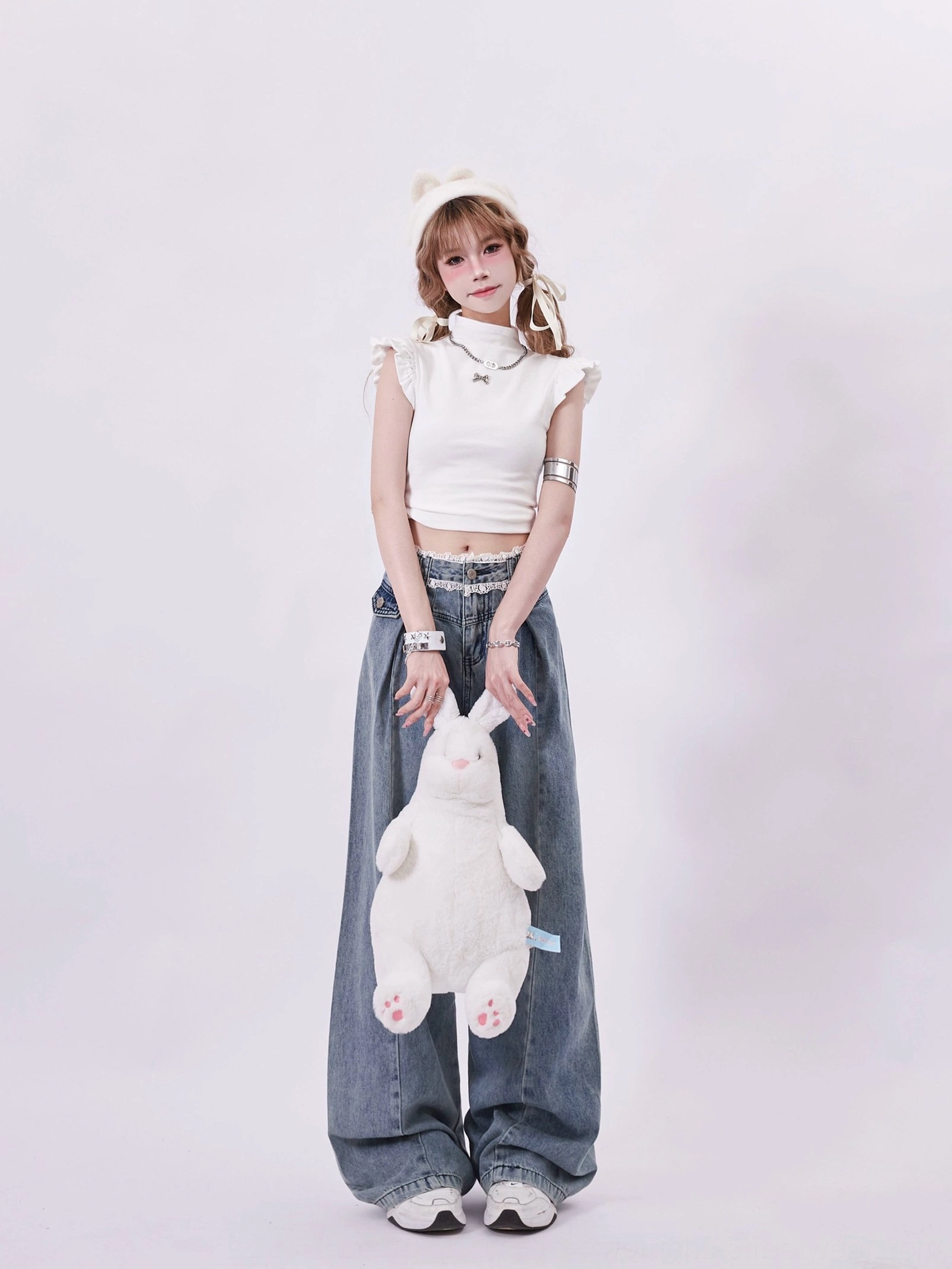 Women’s white ruffle sleeve mock neck crop top with bow pin styled in a Korean Y2K streetwear outfit with wide leg jeans