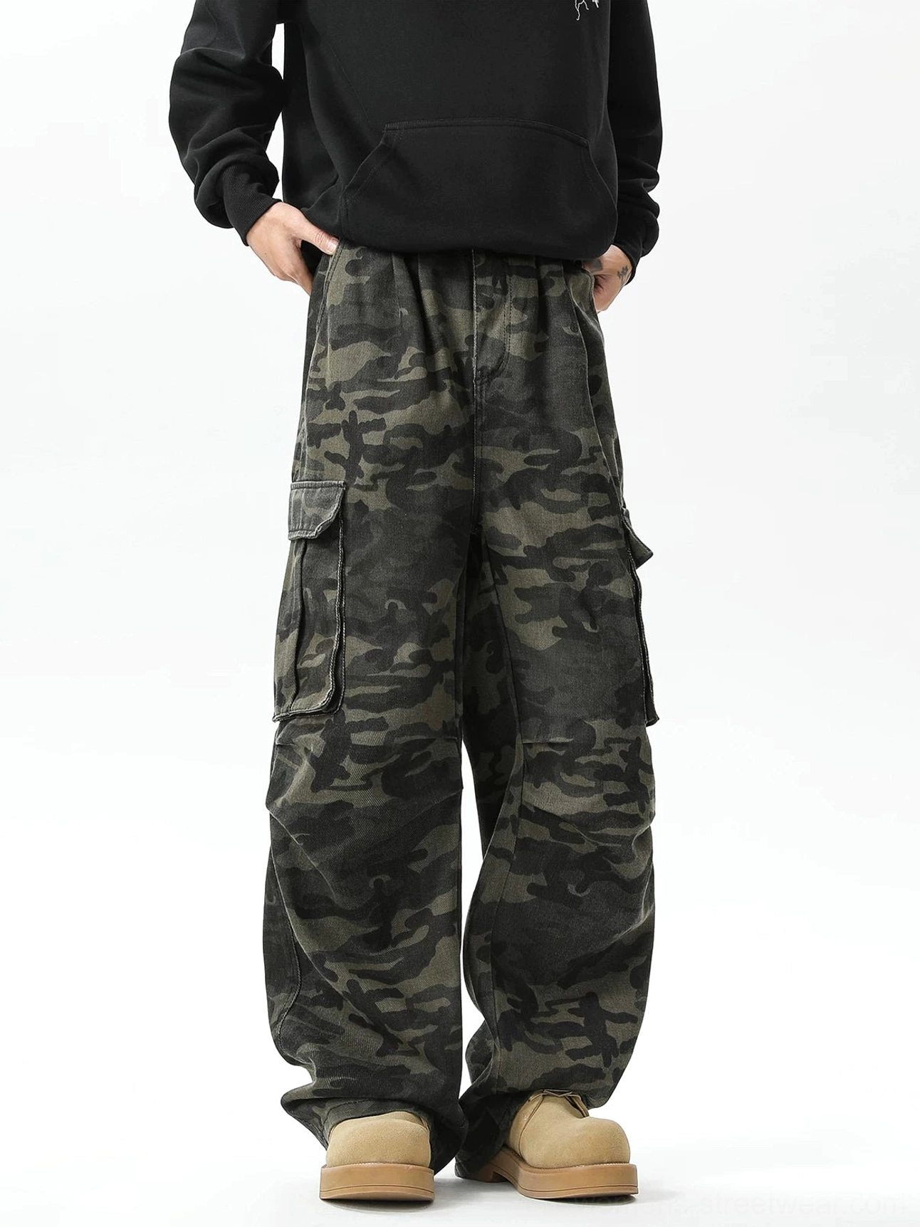 Front view of relaxed wide-leg camouflage streetwear cargo pants showing the elastic waistband, hidden drawstring, side pockets, and oversized utility silhouette