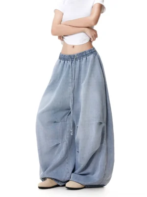 Close-up view of women's wide-leg drawstring jeans showing the elastic waist, front drawstring, button detail, and soft crinkled washed denim texture