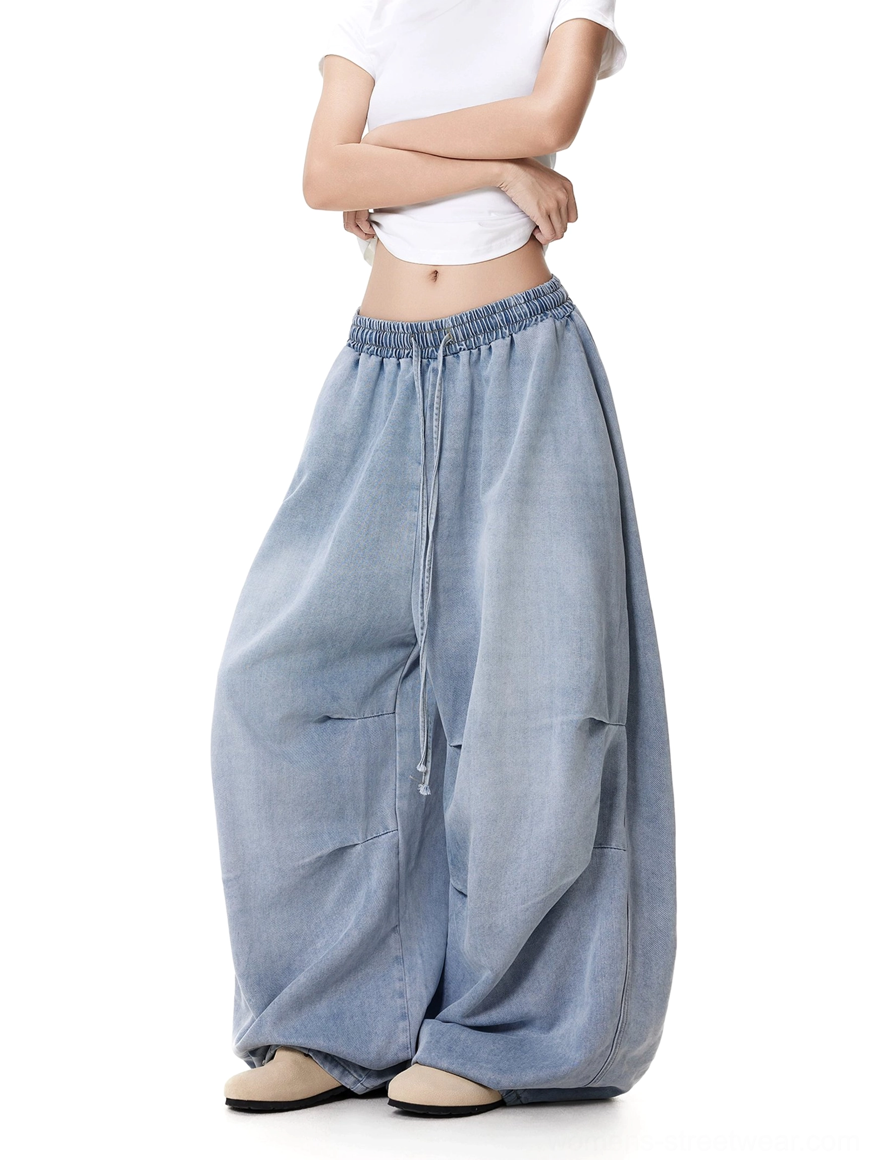 Close-up view of women's wide-leg drawstring jeans showing the elastic waist, front drawstring, button detail, and soft crinkled washed denim texture