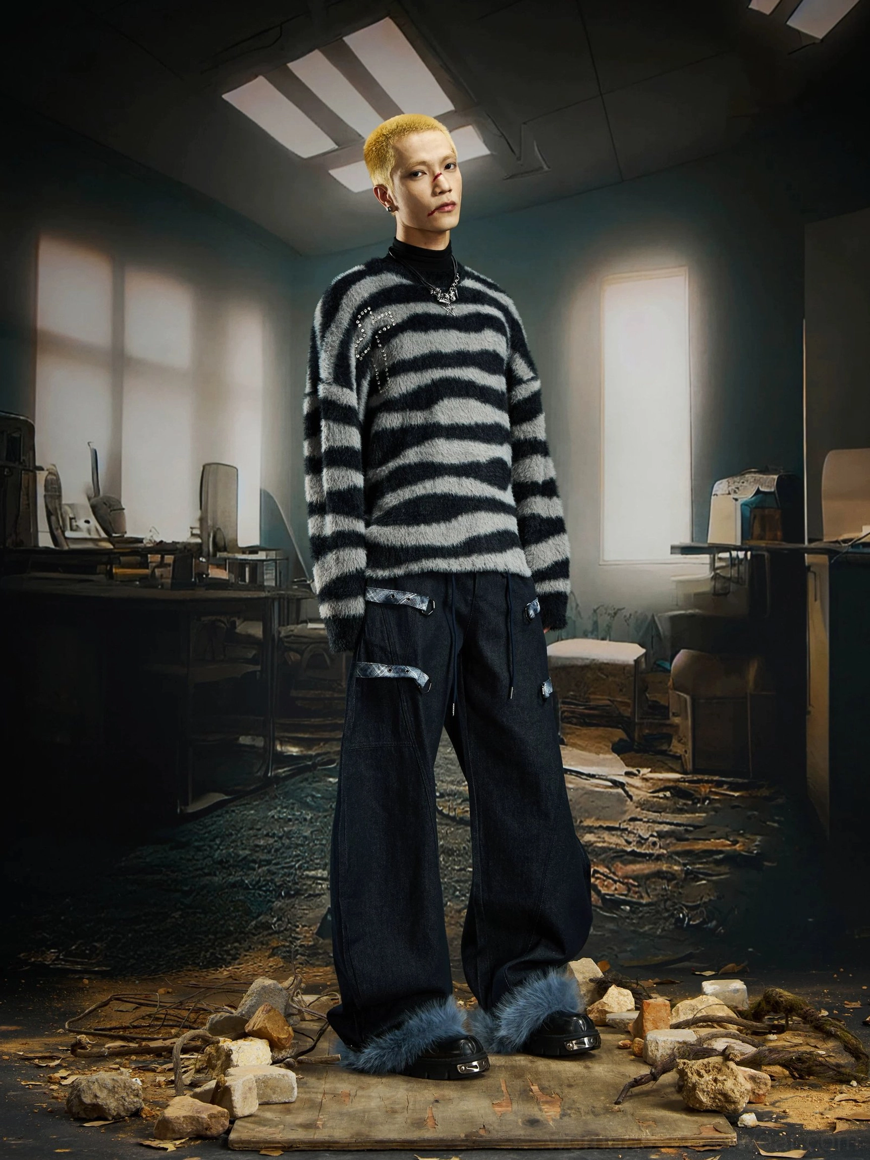 Male streetwear model wearing wide-leg fur-hem cargo pants with decorative straps and striped knit sweater